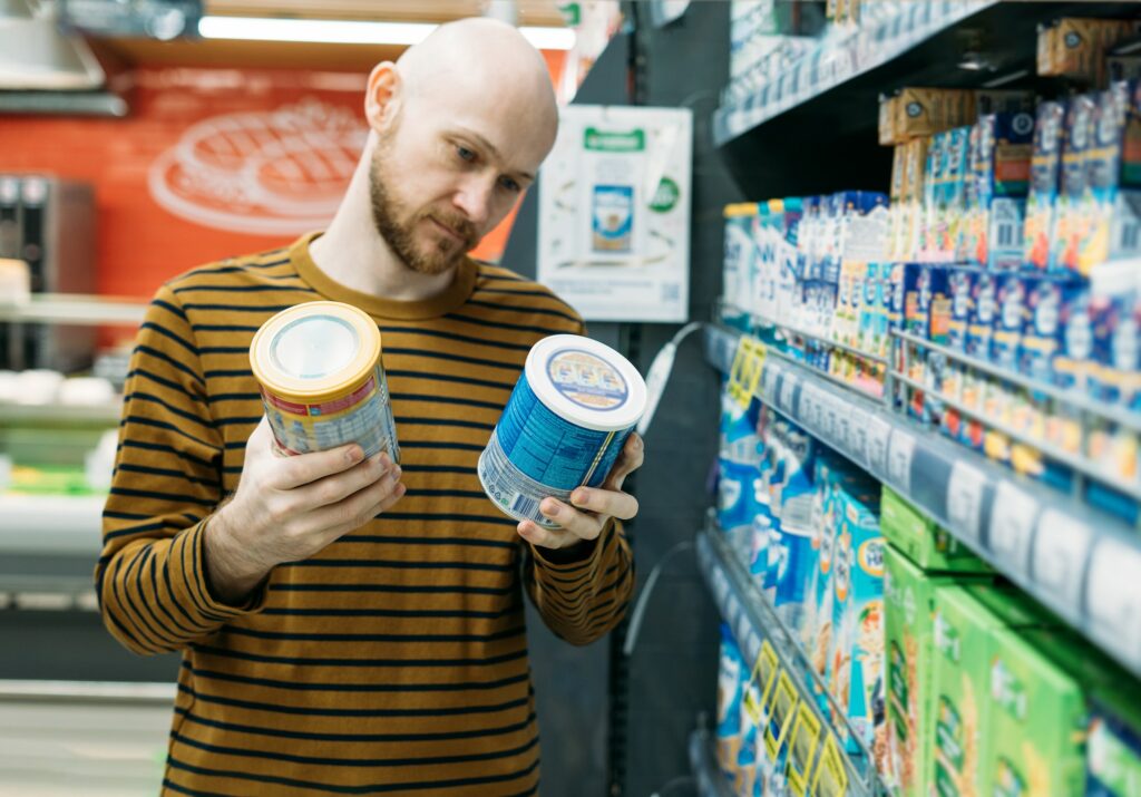Bearded man in casual clothes choose baby powdered milk in supermarket